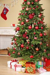 Decorated Christmas tree with gifts in room closeup