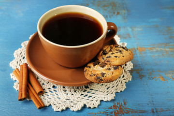 Glass cup of coffee and tasty cookie on color wooden background