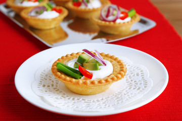 Tartlets with greens and vegetables with sauce on plate and