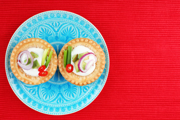 Tartlets with greens and vegetables with sauce on plate on