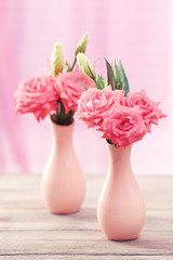 Beautiful flowers in vases on table on curtains background