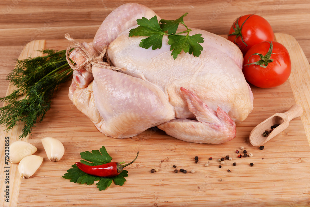 Wall mural Raw chicken on wooden table