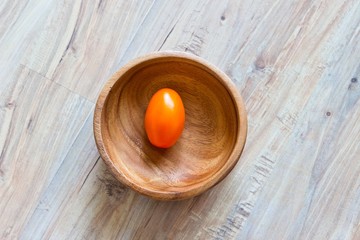 Fresh orange tomato in wooden bowl
