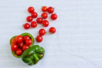 Small tomatoes in cut green pepper at white linen background