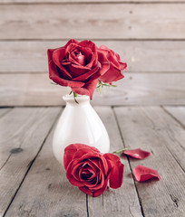 Red rose in vase on wooden table