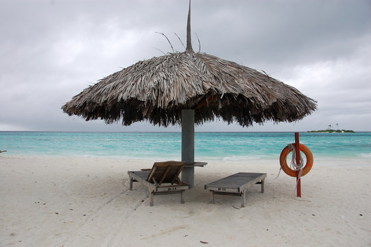 Beach umbrella and sun lounger with lifebuoy at Maldives