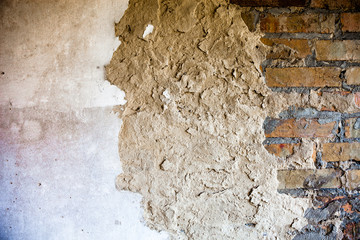 Old brick wall with the damaged plaster
