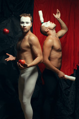 Freak circus concept. Two muscular mime artists, clowns juggling
