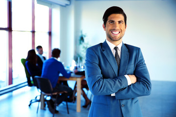 Cheerful businessman standing with arms folded