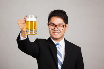 Asian businessman cheers with mug of beer