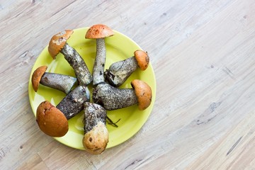Fresh mushrooms in yellow dish on wooden background