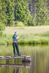 Fototapeta na wymiar young woman fishing on pier at pond