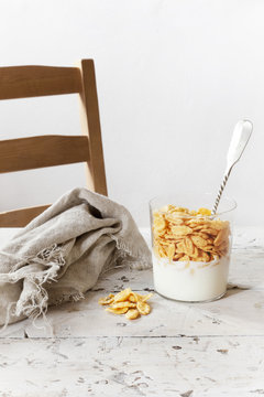 breakfast with white yogurt and corn flakes on glass with spoon