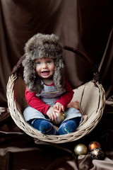 Laughing baby  sitting in the basket with Christmas balls - obrazy, fototapety, plakaty