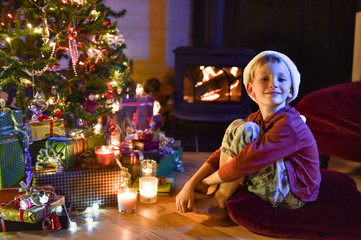 Christmas night a little boy with a santa hat sitting on a cushi
