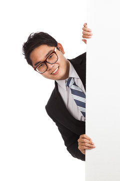 Asian businessman peeking from behind blank banner