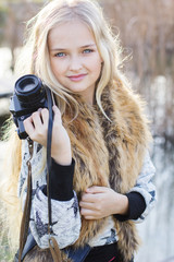 Cute little girl is resting near lake with camera