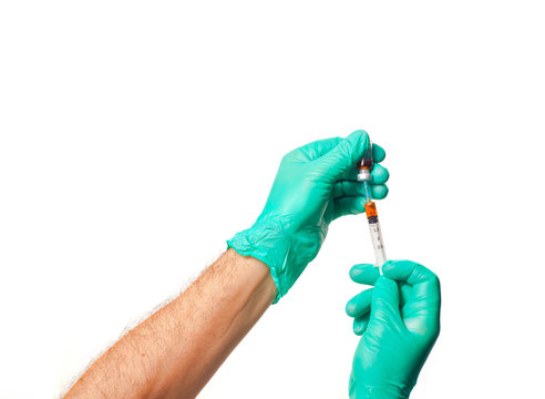 Hands of the doctors with green gloves filling a syringe