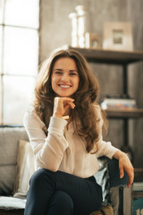 Smiling young woman sitting on couch in loft apartment