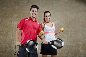 Paddle tennis couple posing in concrete court