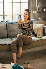 Obraz premium Young woman making selfie in loft apartment
