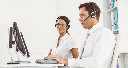 Business people with headsets using computers in office