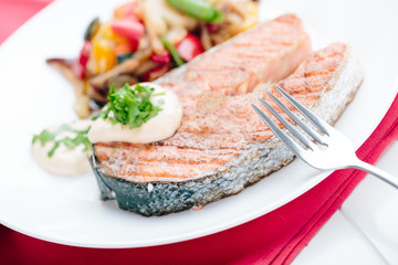 Grilled Salmon with Fresh vegetables on red background