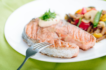 Grilled Salmon with Fresh vegetables on green background