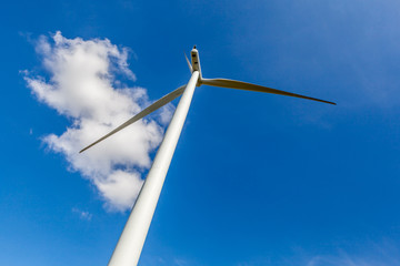 Low angle view of wind turbine against cloudy blue sky in wind f