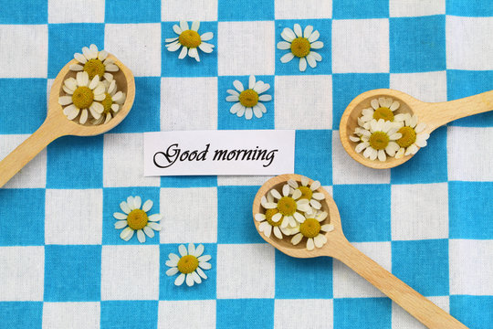 Good morning card with fresh chamomile flowers on wooden spoons