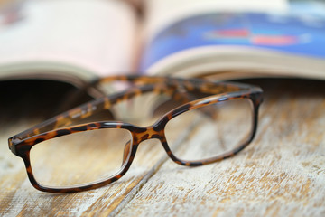 Reading glasses and open book on rustic wooden surface