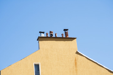 Chimney section of yellow housewall with different chimney caps
