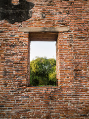 Ruin and ancient orange brick wall with a window view to the tre