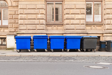 Grosse fahrbare Müllcontainer stehen aufgereiht am Strassenrand