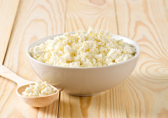 Cottage cheese in porcelain bowl with wooden spoon