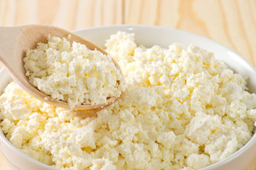 Cottage cheese in porcelain bowl with wooden spoon