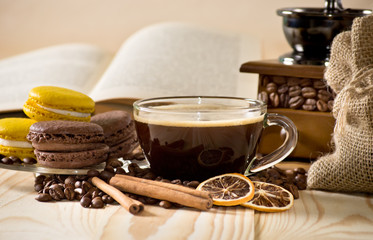 Obraz na płótnie Canvas Coffee cup with macaroon, cinnamon and dried lemon