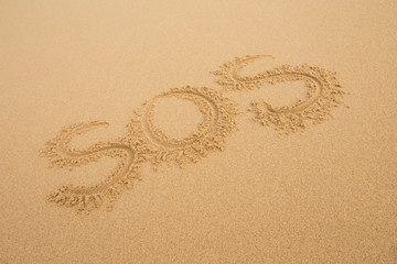 Fototapeta na wymiar SOS - Inscription on the sand of tropical beach