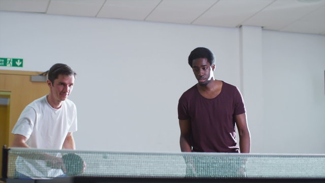 Two men playing table tennis doubles and winning