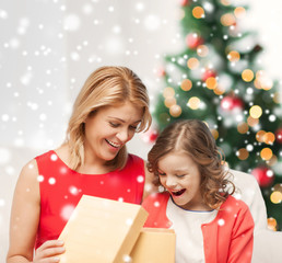 smiling mother and daughter with gift box at home