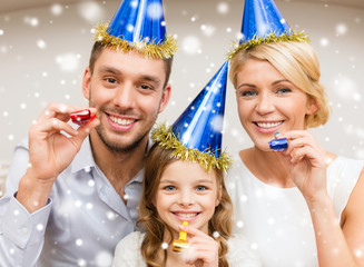 smiling family in party hats blowing favor horns