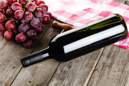 bottle of wine corkscrew amd grapes on wooden table