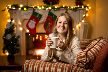 woman sitting at fireplace with cup of tea at Christmas