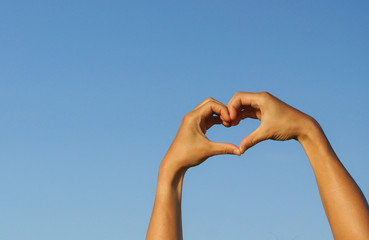 hands forming a heart shape with blue sky