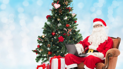 man in costume of santa claus with laptop