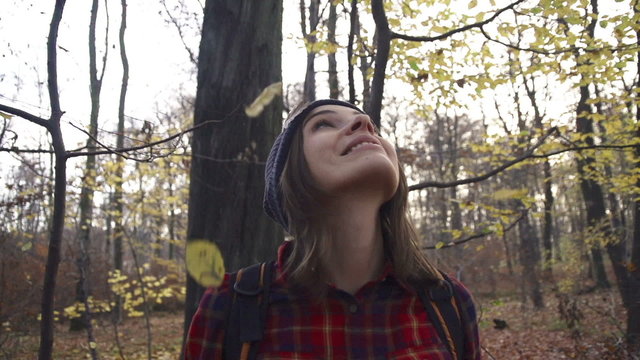 Happy woman enjoying falling leaves in forest, super slow motion