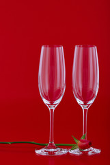 Two wine glasses with rose flower over red