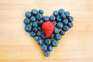 Heart made of blueberries with strawberry in centre