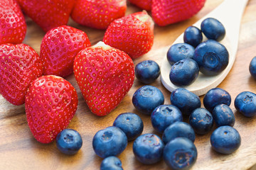Blueberries on wooden spoon with strawberries