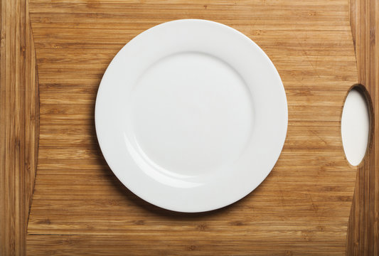 Empty white plate on wooden board